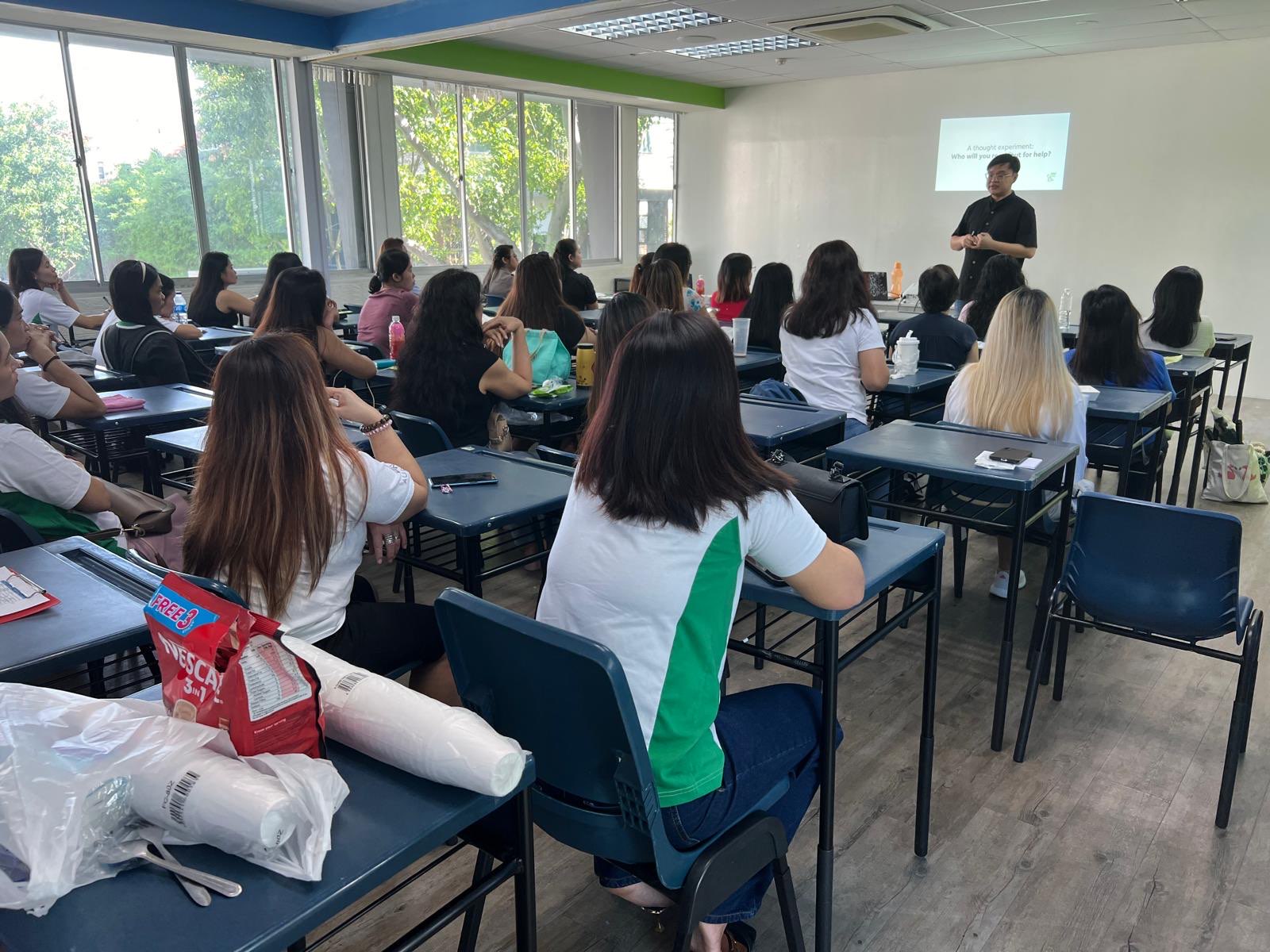 Students sitting in a classroom facing a teacher as he conducts the lesson